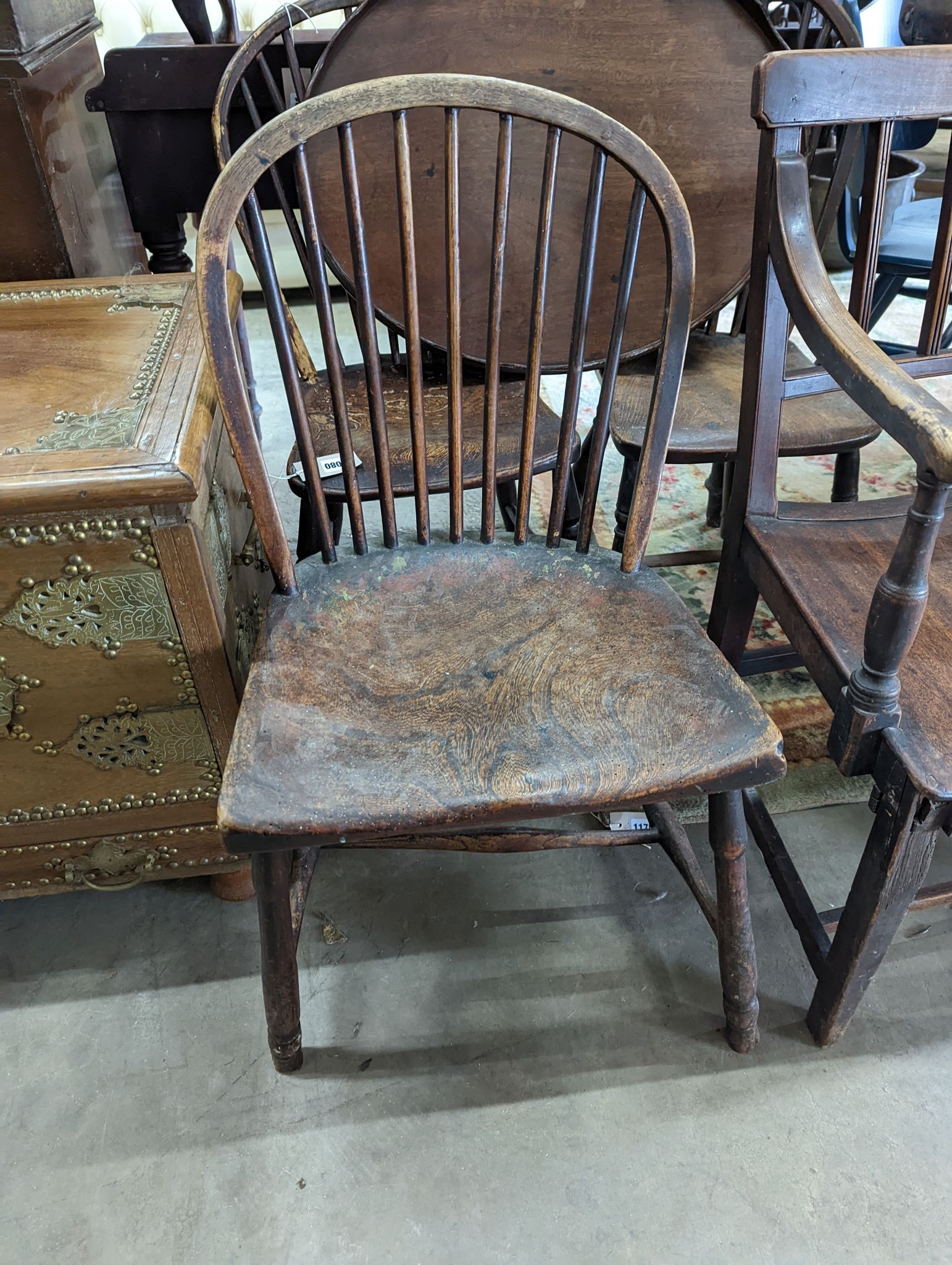 A 19th century elm and ash primitive Windsor comb back chair with traces of original paint, two other Windsor comb back chairs, a George III provincial elbow chair and an oval mahogany tea tray